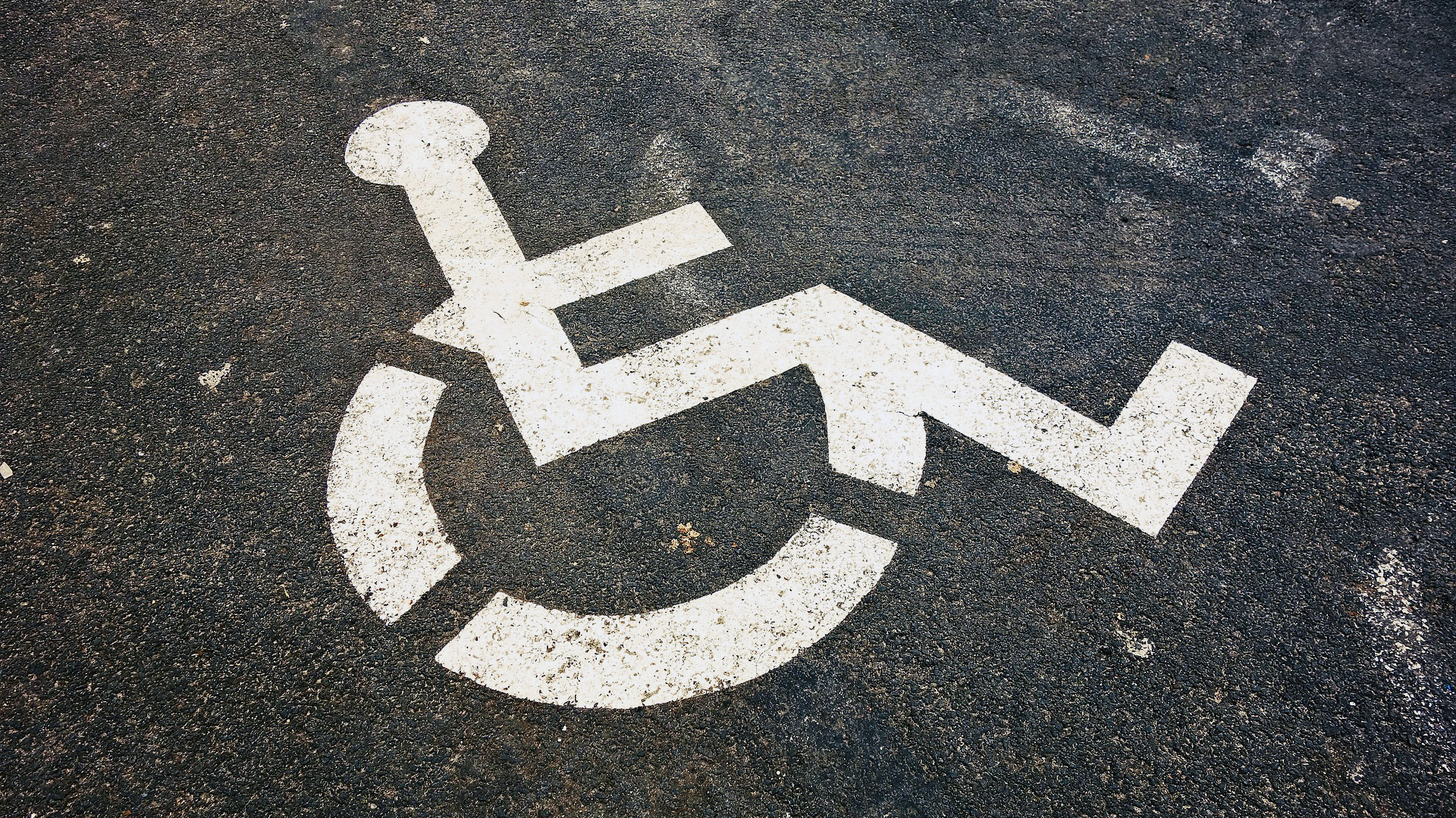 A white stickman in a wheelchair painted on blacktop.