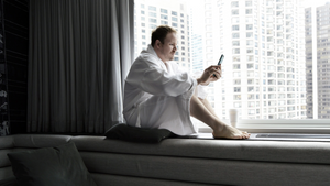 A man in a white robe who is entering information into his cell phone.